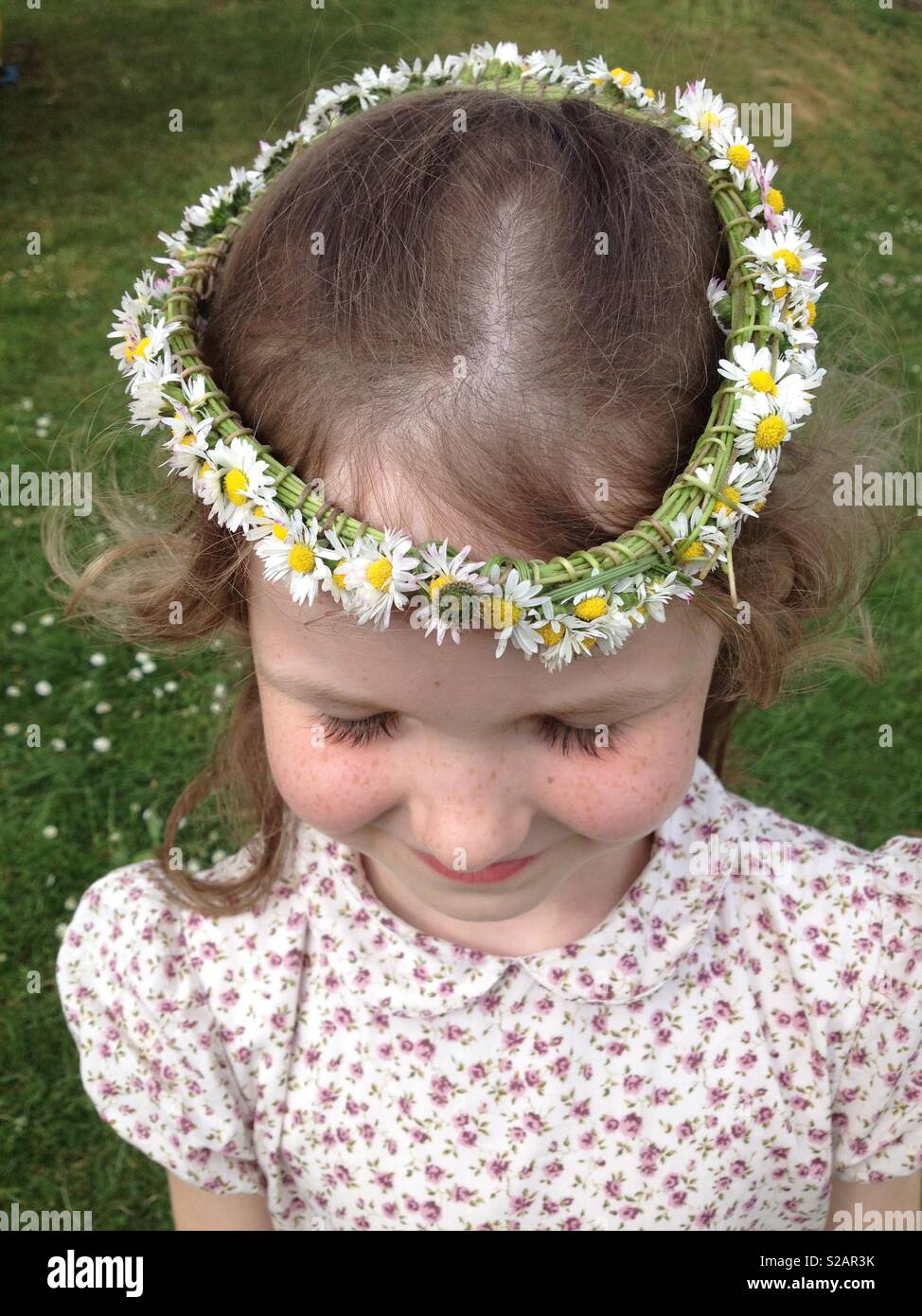 Sei-anno-vecchia ragazza con una catena a margherita sulla sua testa, a forma di corona. Foto Stock