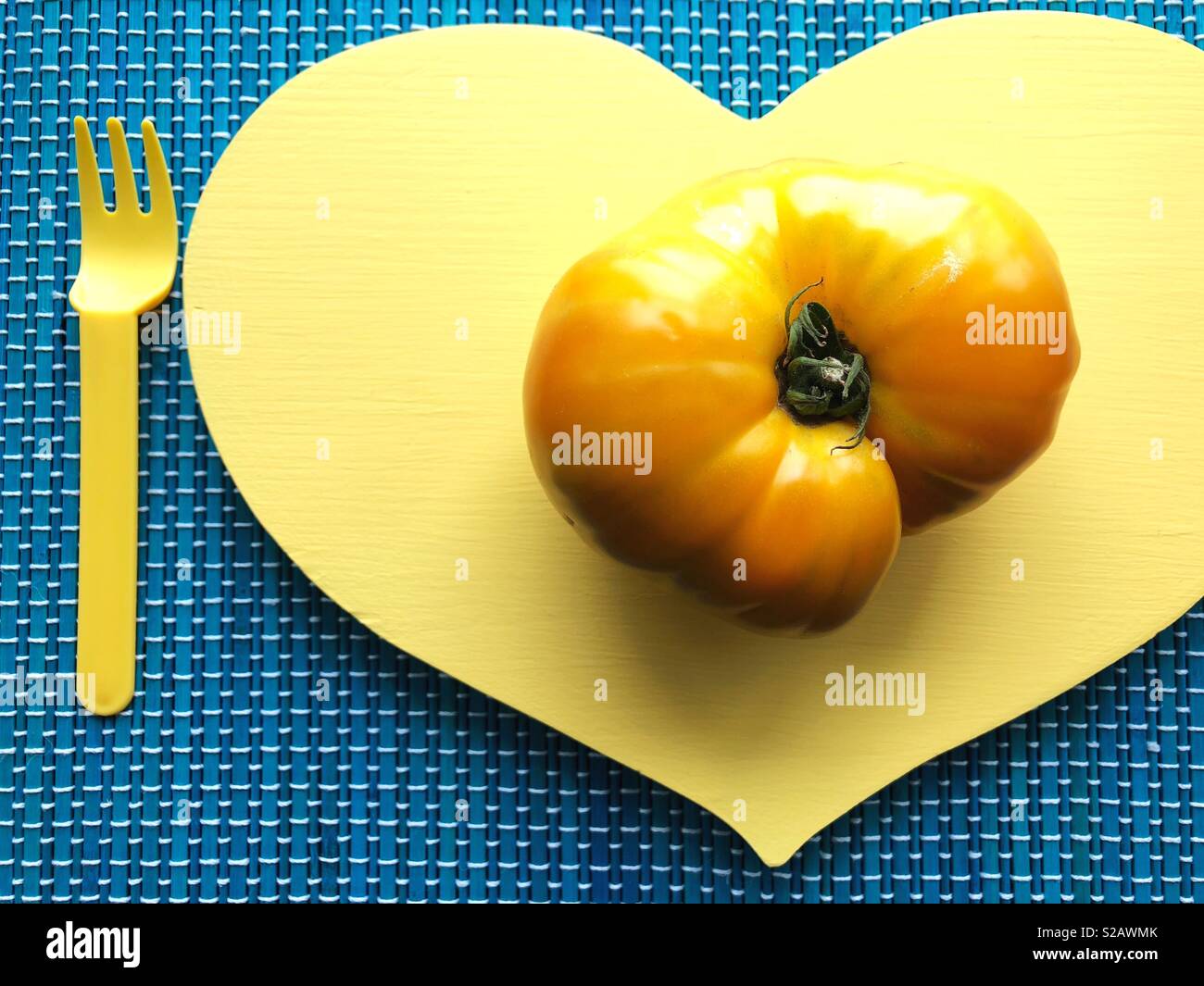 Un cimelio di giallo pomodoro su un cuore a forma di lastra. Foto Stock