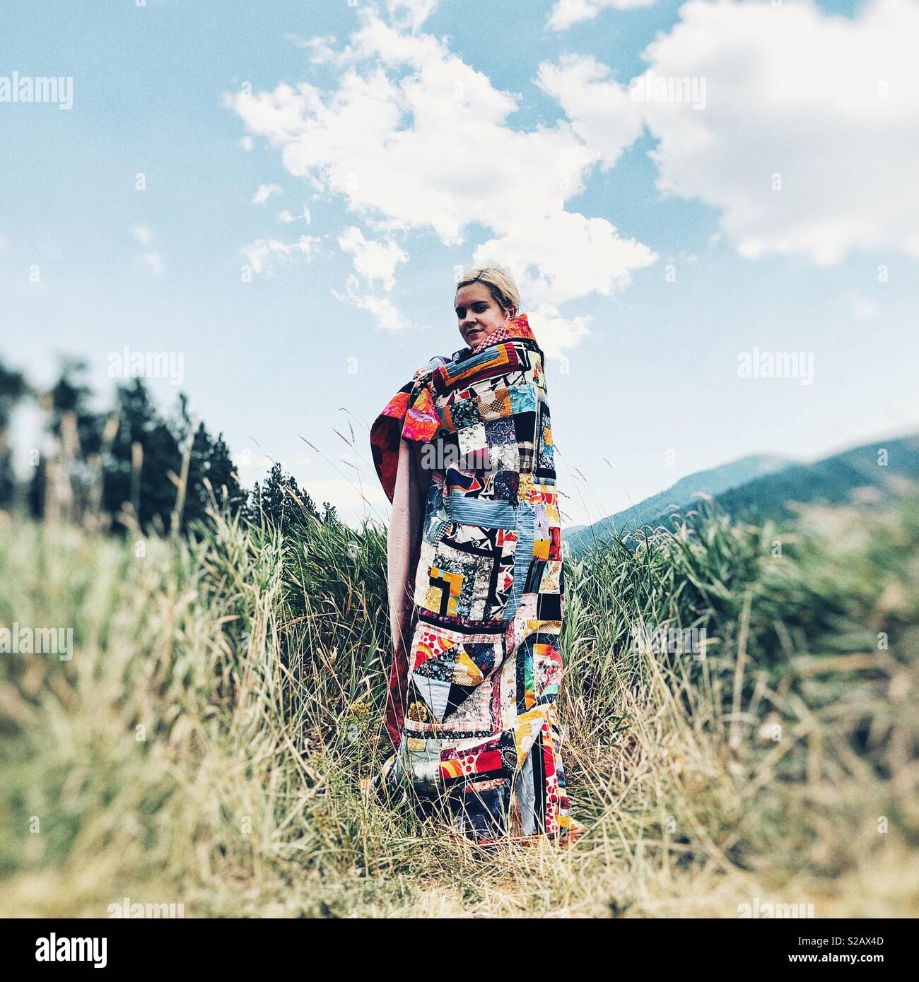 Ragazza avvolto in moderno coperta di quilt dà un aspetto misterioso Foto Stock