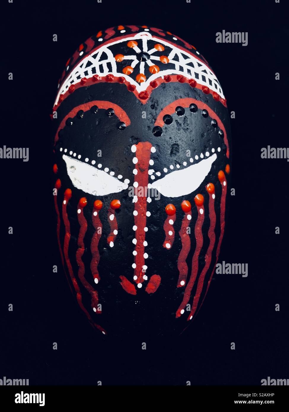 Un rituale africana maschera tribale dipinta su una pietra. Foto Stock