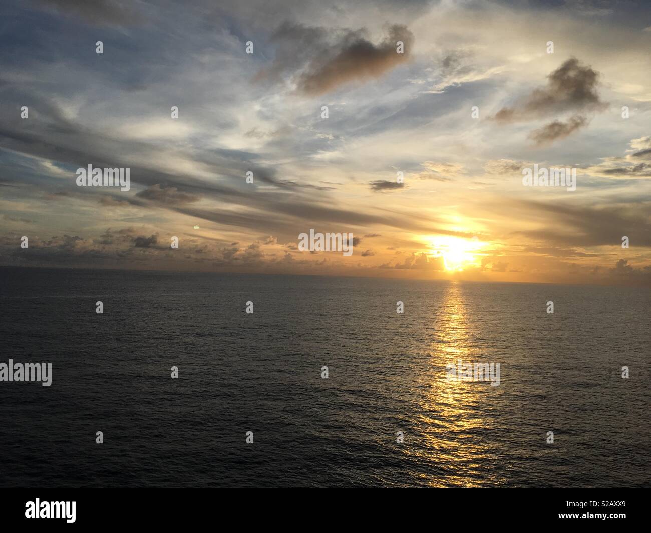 Il tramonto sopra la calma Oceano Atlantico in un giorno nuvoloso. Foto Stock