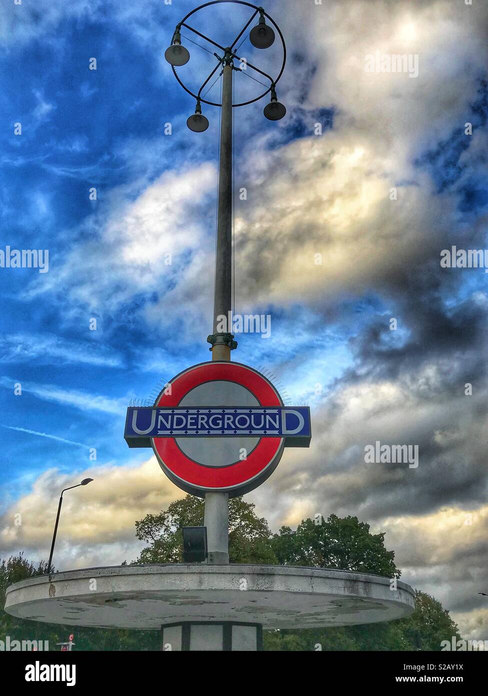 Art Deco London Underground segno, contro una drammatica del cielo della sera. Foto Stock