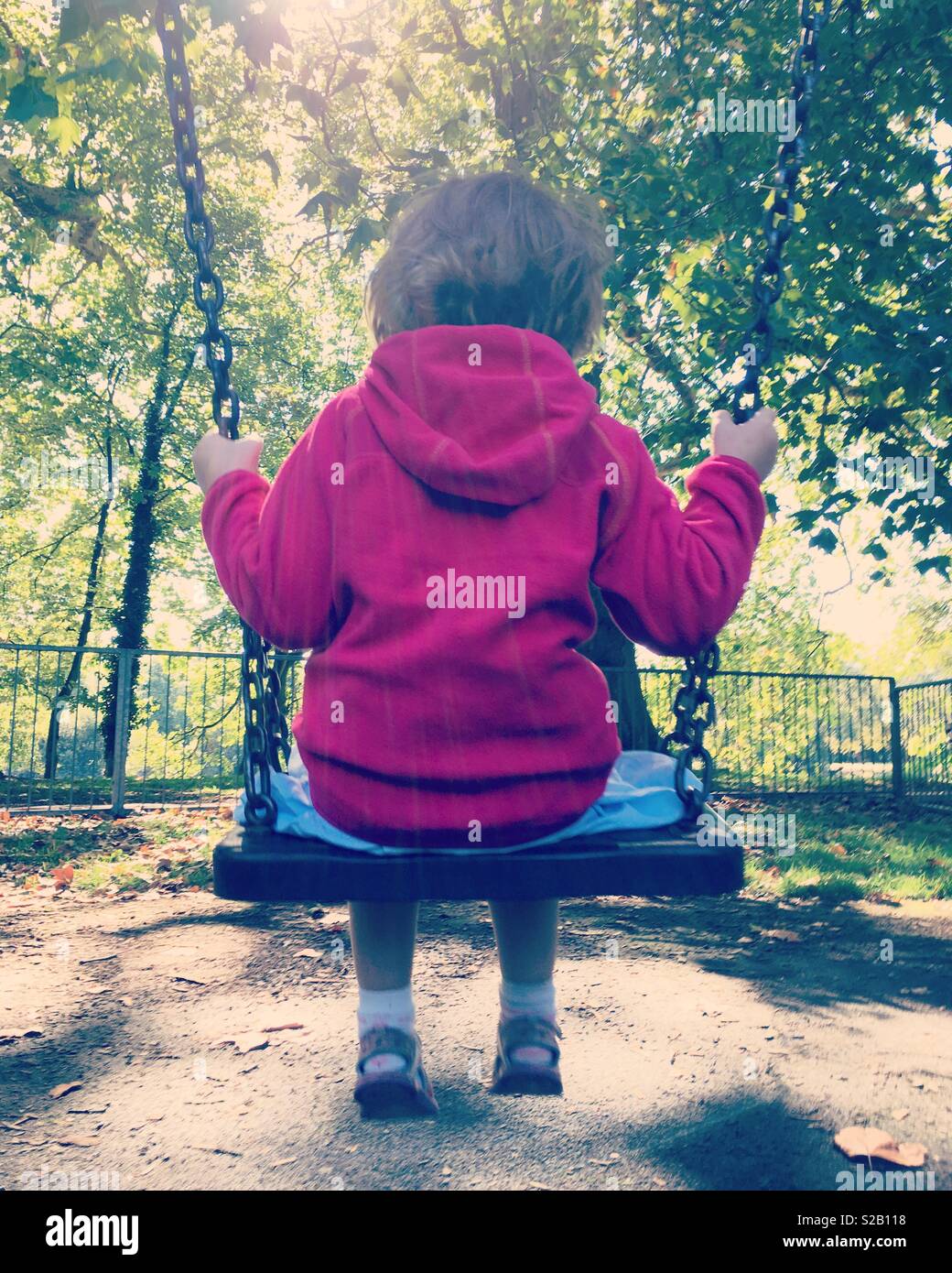 Retrò Instagram foto di una bambina 4 anni / di età compresa tra i quattro anni di oscillazione sull'altalena in altalena parco con alberi e foglie. Regno Unito Foto Stock