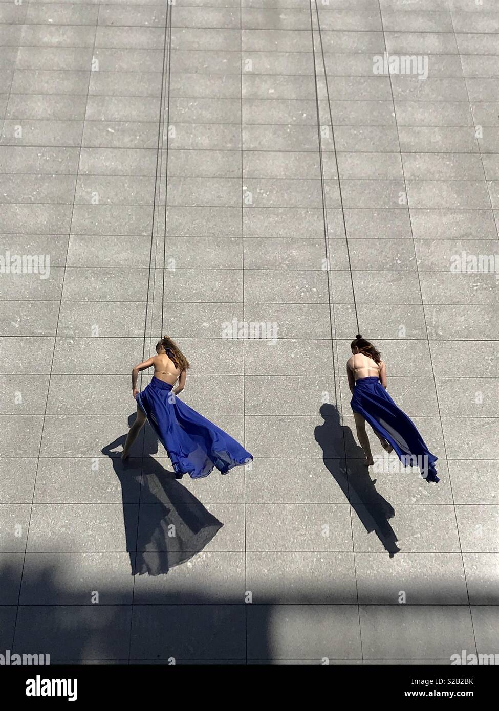 Due donne di cordata lungo il lato di un edificio in lunghi fluenti abiti blu in Dublino Irlanda. Foto Stock