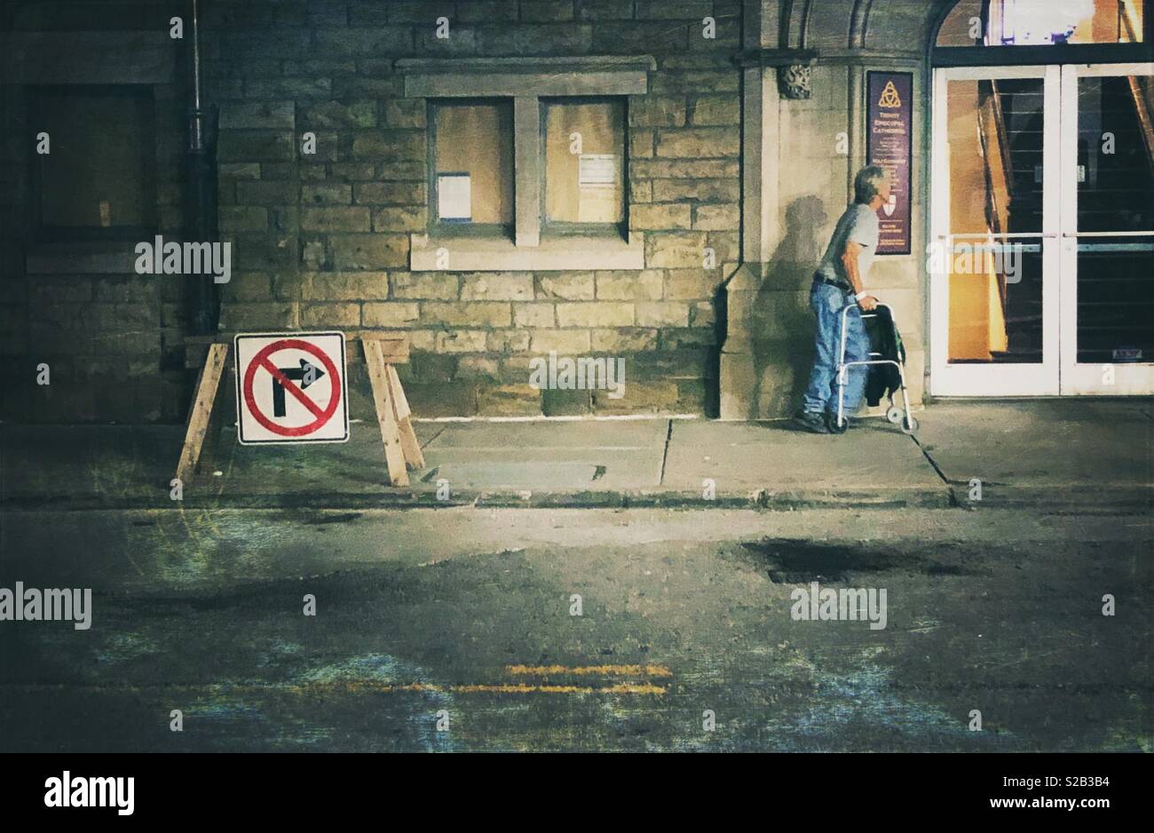 Una scena di strada di un uomo con un viandante che passa da un segno che indica assenza di sterzata a destra Foto Stock