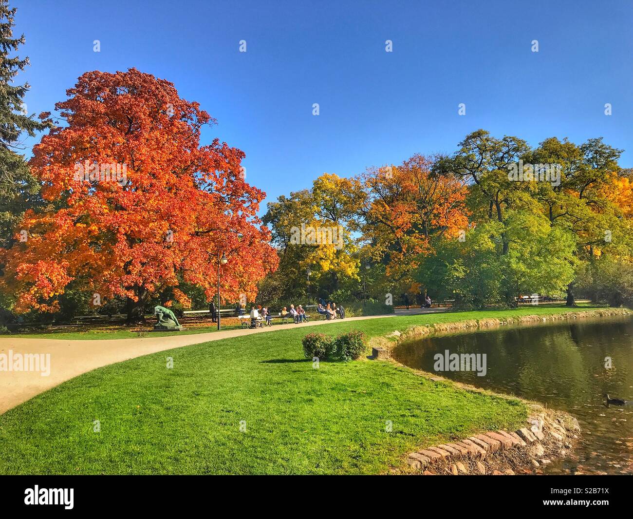 Bellissimi colori autunnali e persone relax su una panchina in una calda giornata d'autunno in un Parco Lazienki, Varsavia, Polonia Foto Stock