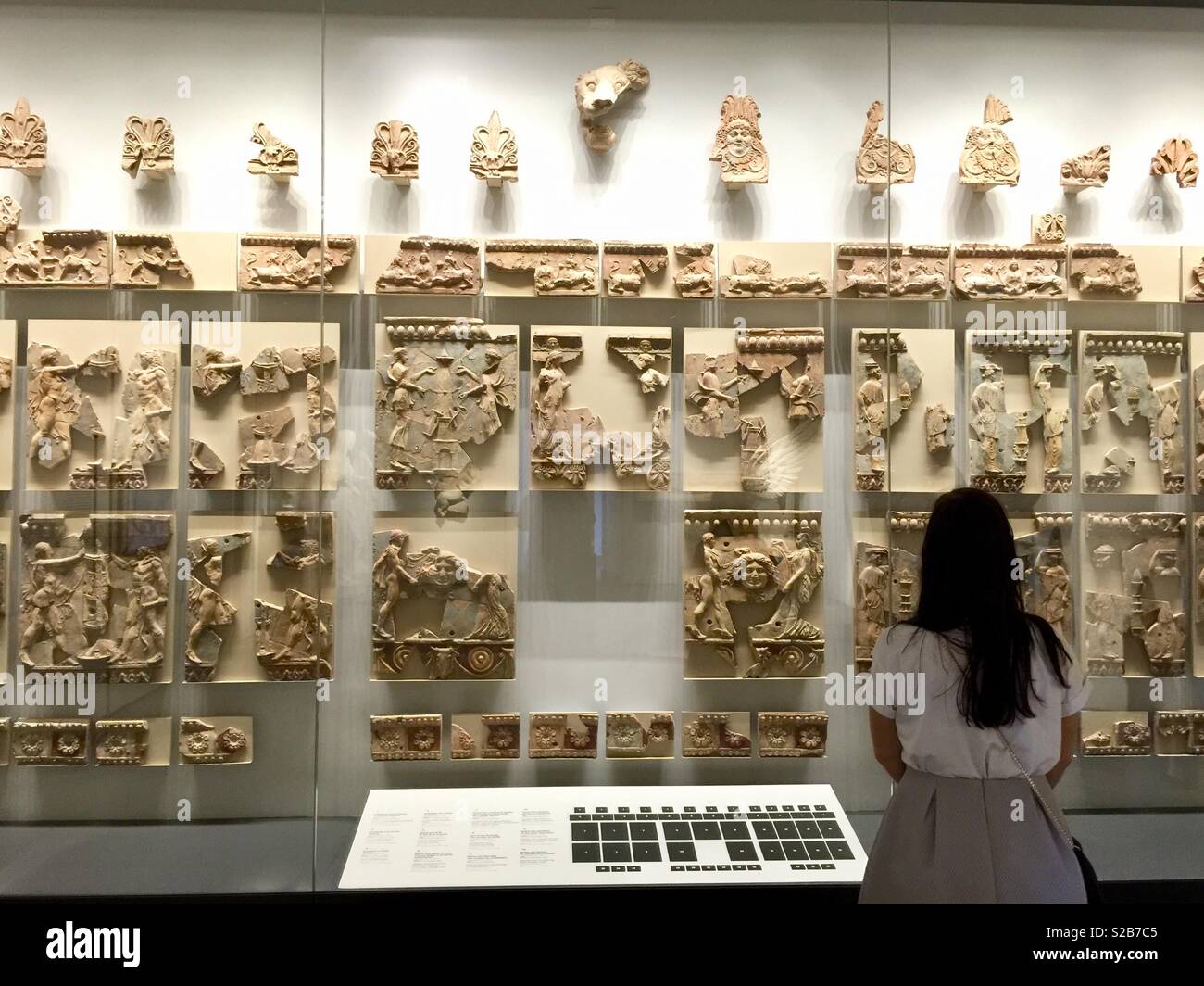 Un visitatore ammirando le decorazioni di un tempio romano nel museo sul colle Palatino in Roma, Italia Foto Stock