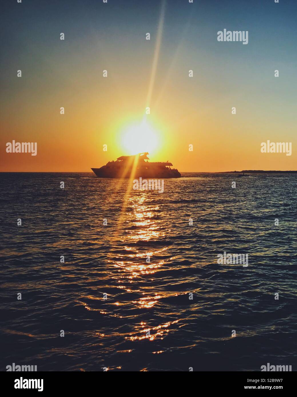 Tramonto al mare dietro la silhouette della barca Foto Stock