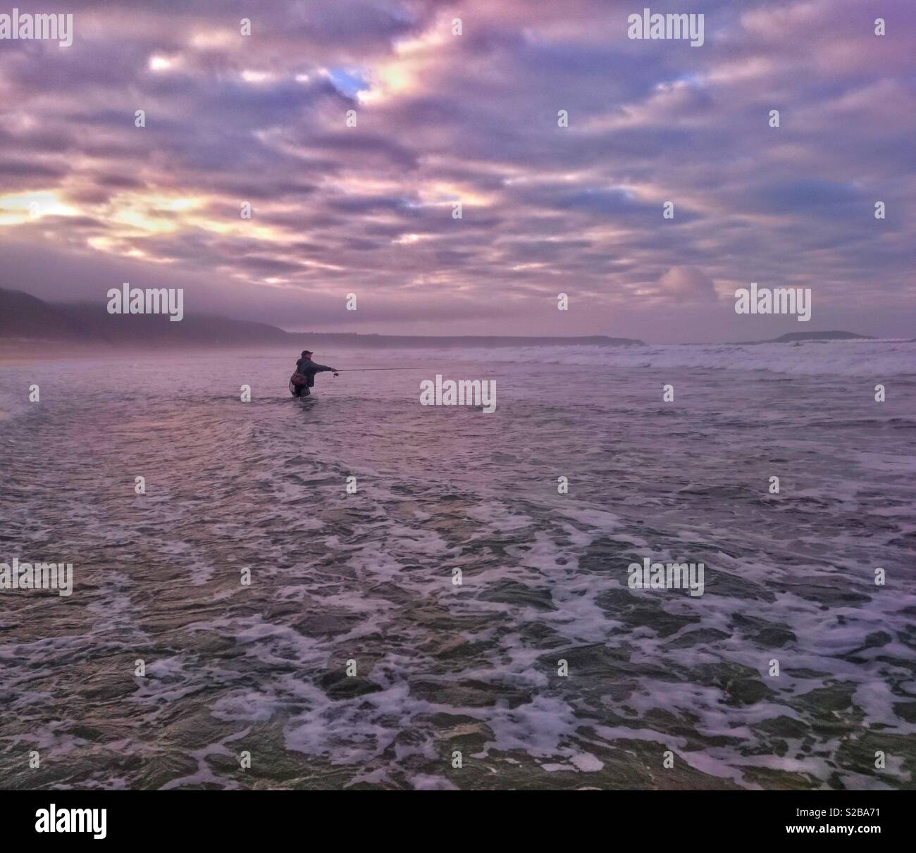 Il pescatore pesca di Bass nel surf a Llangennith, Gower, Galles. Foto Stock