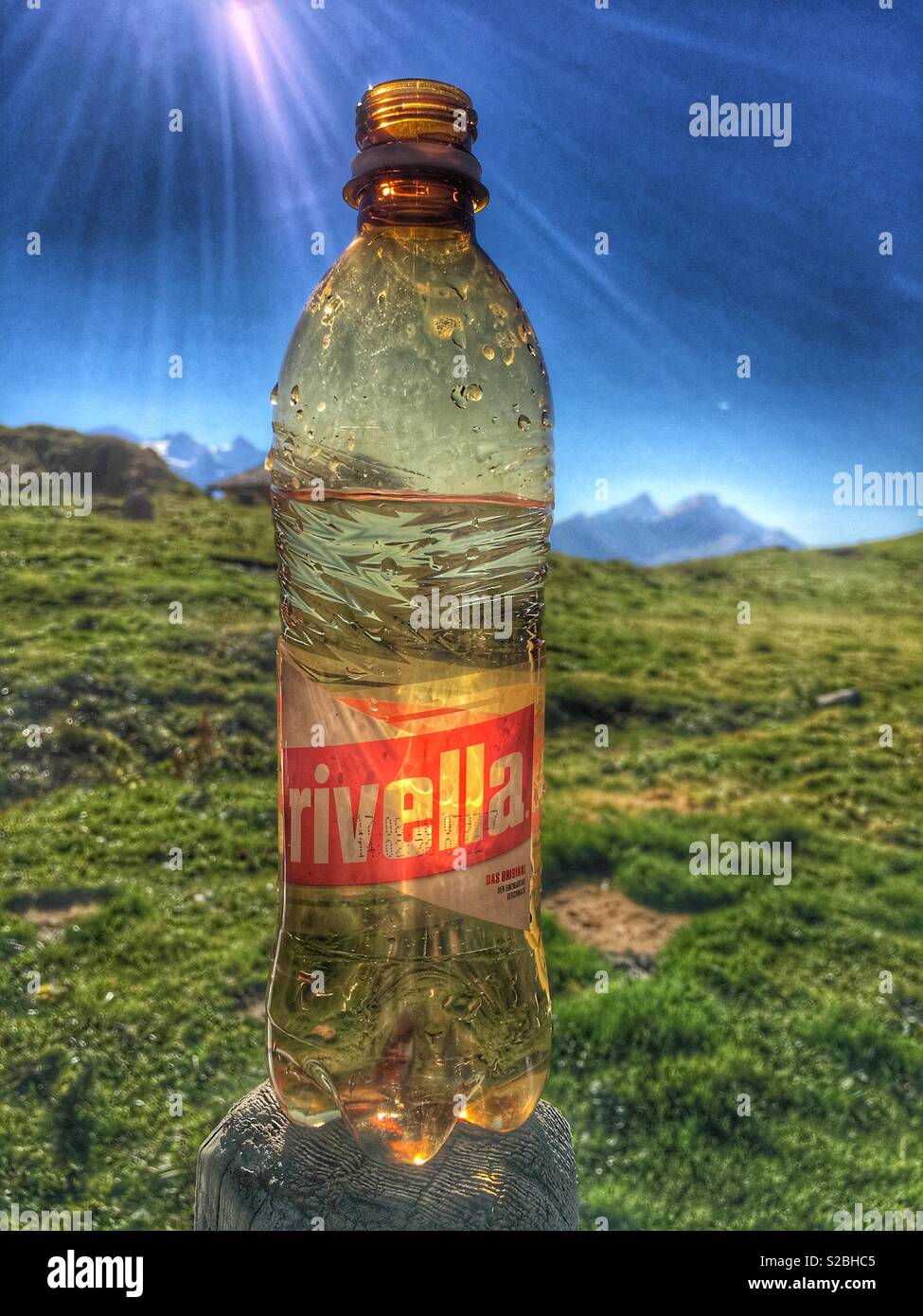 Come fresco come si arriva. Bottiglia di Rivella bere nelle alpi svizzere in un caldo giorno d'estate. Riflessioni. Foto Stock