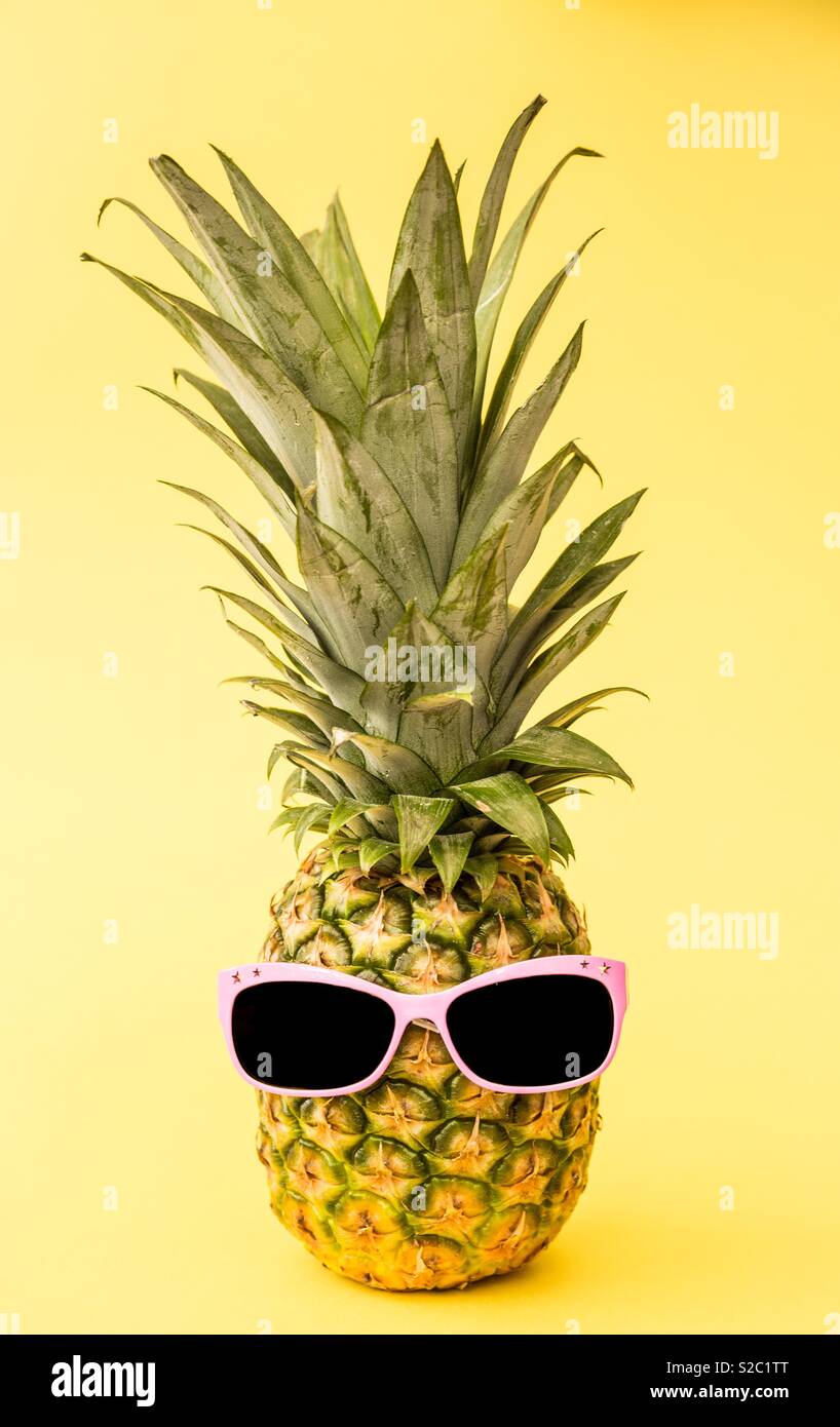 Un divertente di ananas indossando occhiali da sole rosa su sfondo giallo - Immagine stock catturata con smartphone