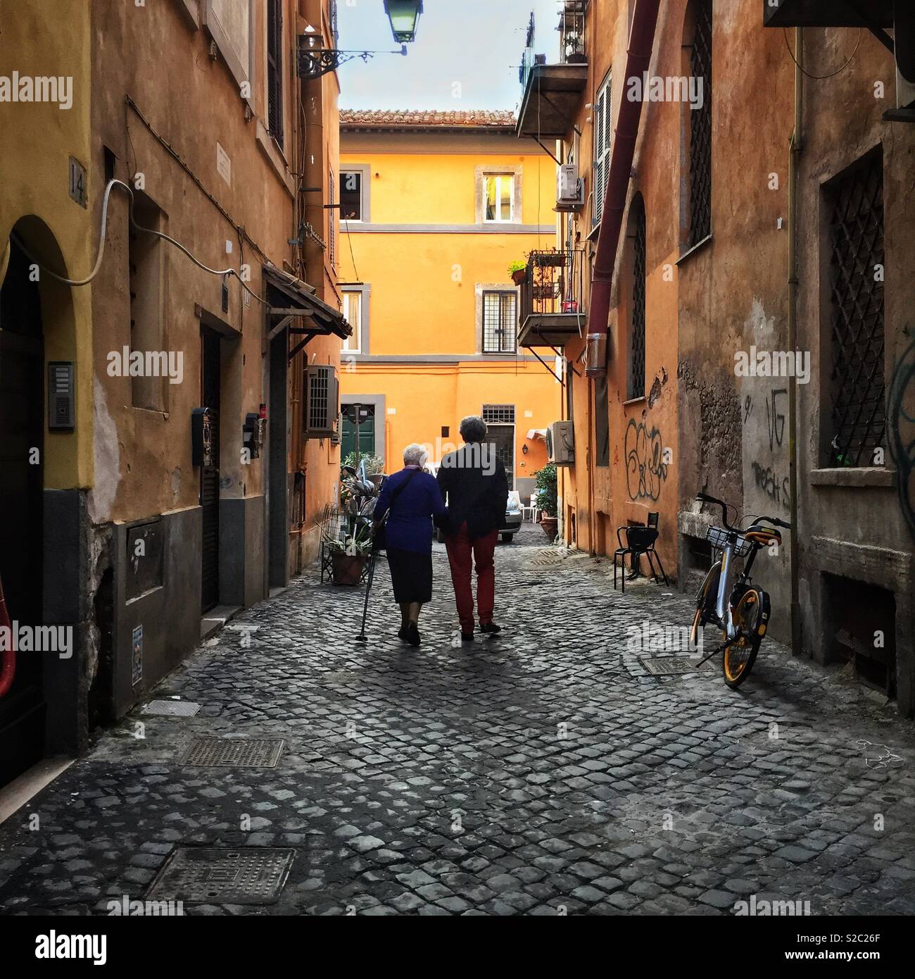 Due persone che camminano su una strada laterale nel quartiere Trastevere di Roma Foto Stock