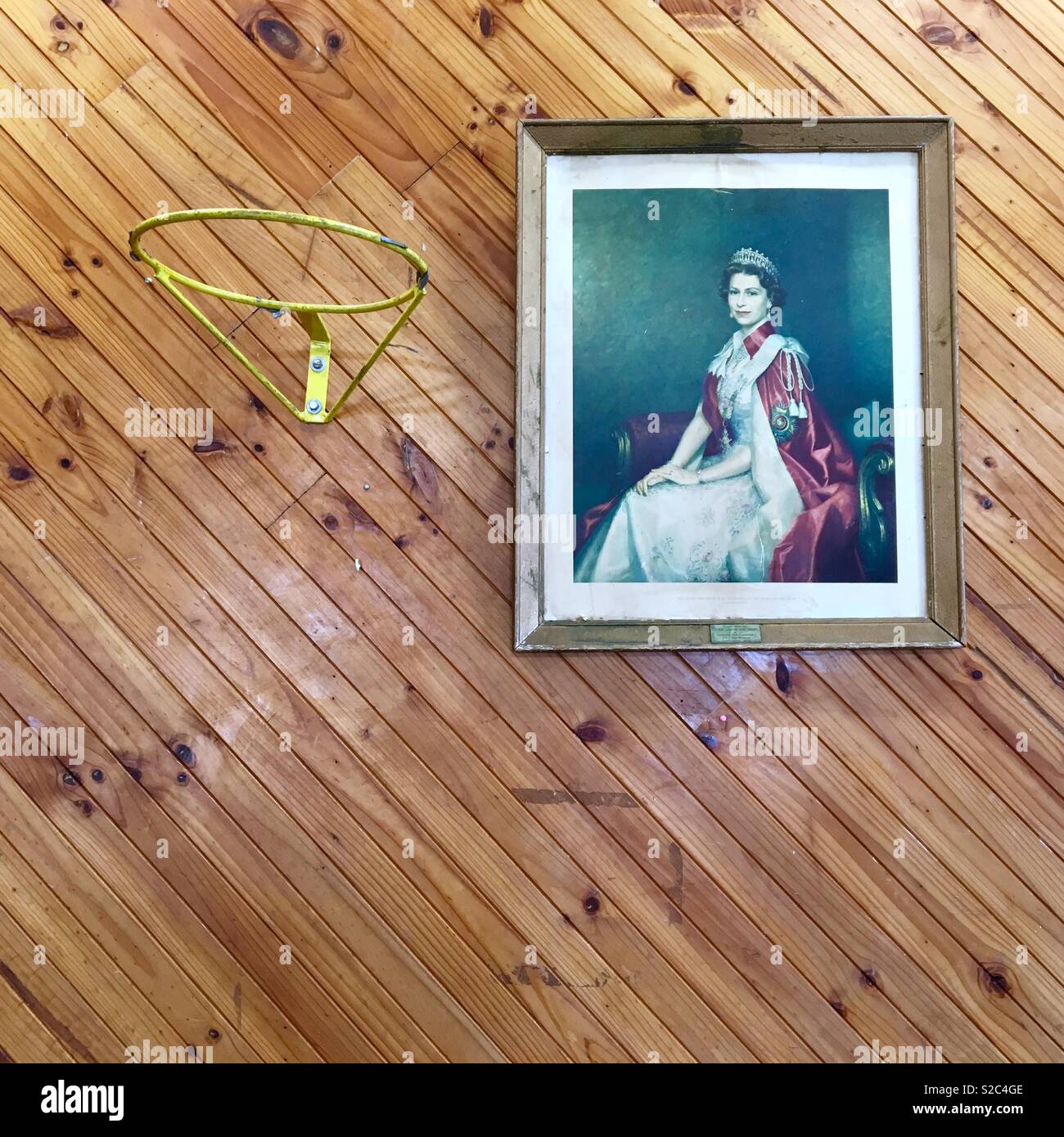 Ritratto incorniciato della regina in una comunità hall con muri con pannelli in legno e un Basketball hoop Foto Stock