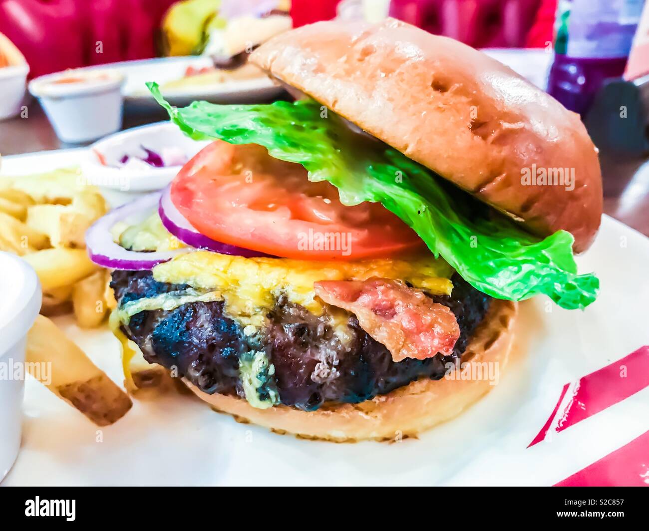 La pancetta e formaggio hamburger con lattuga pomodoro e patate fritte Foto Stock