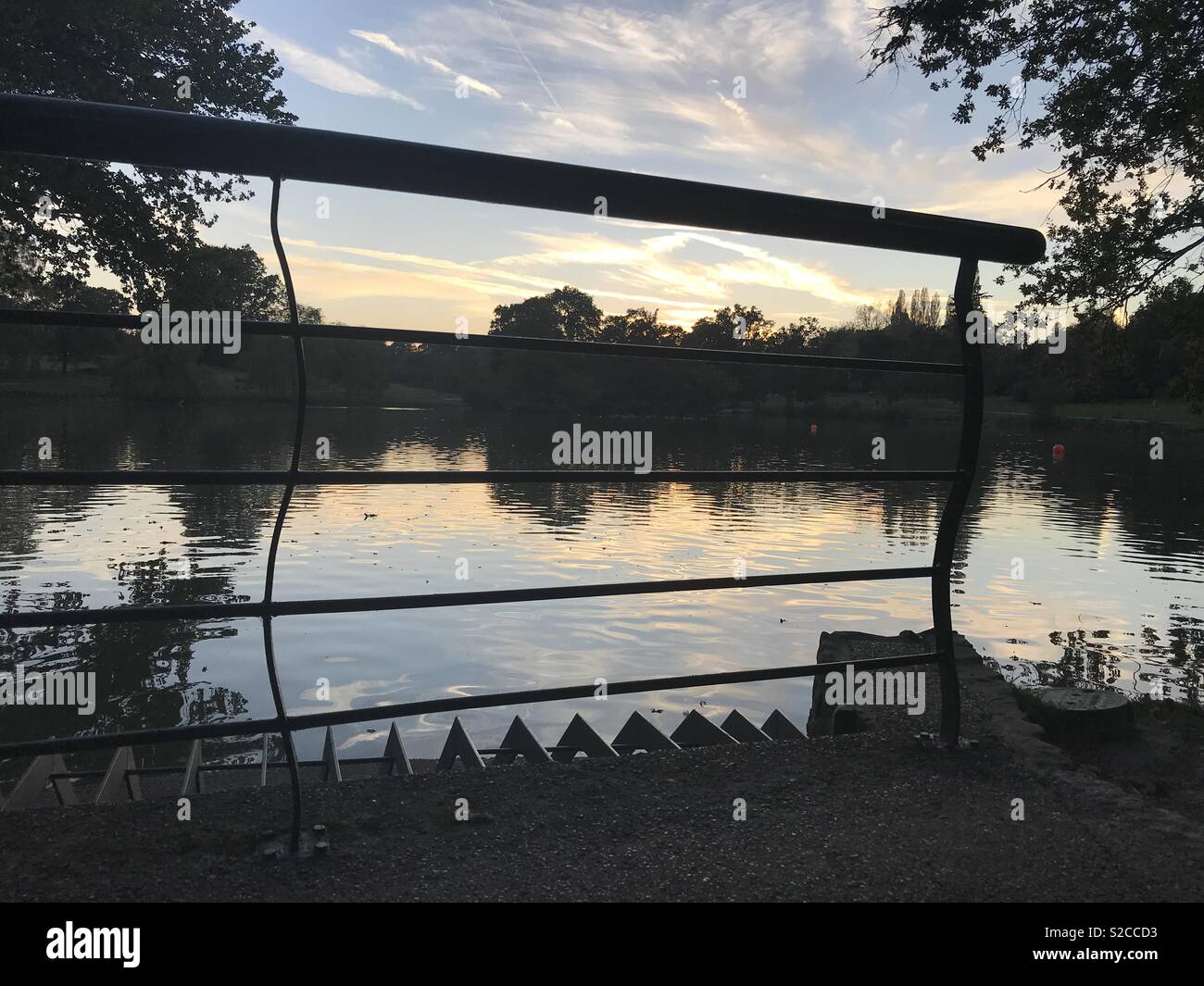 Silhouette di ringhiere con il lago al tramonto Foto Stock