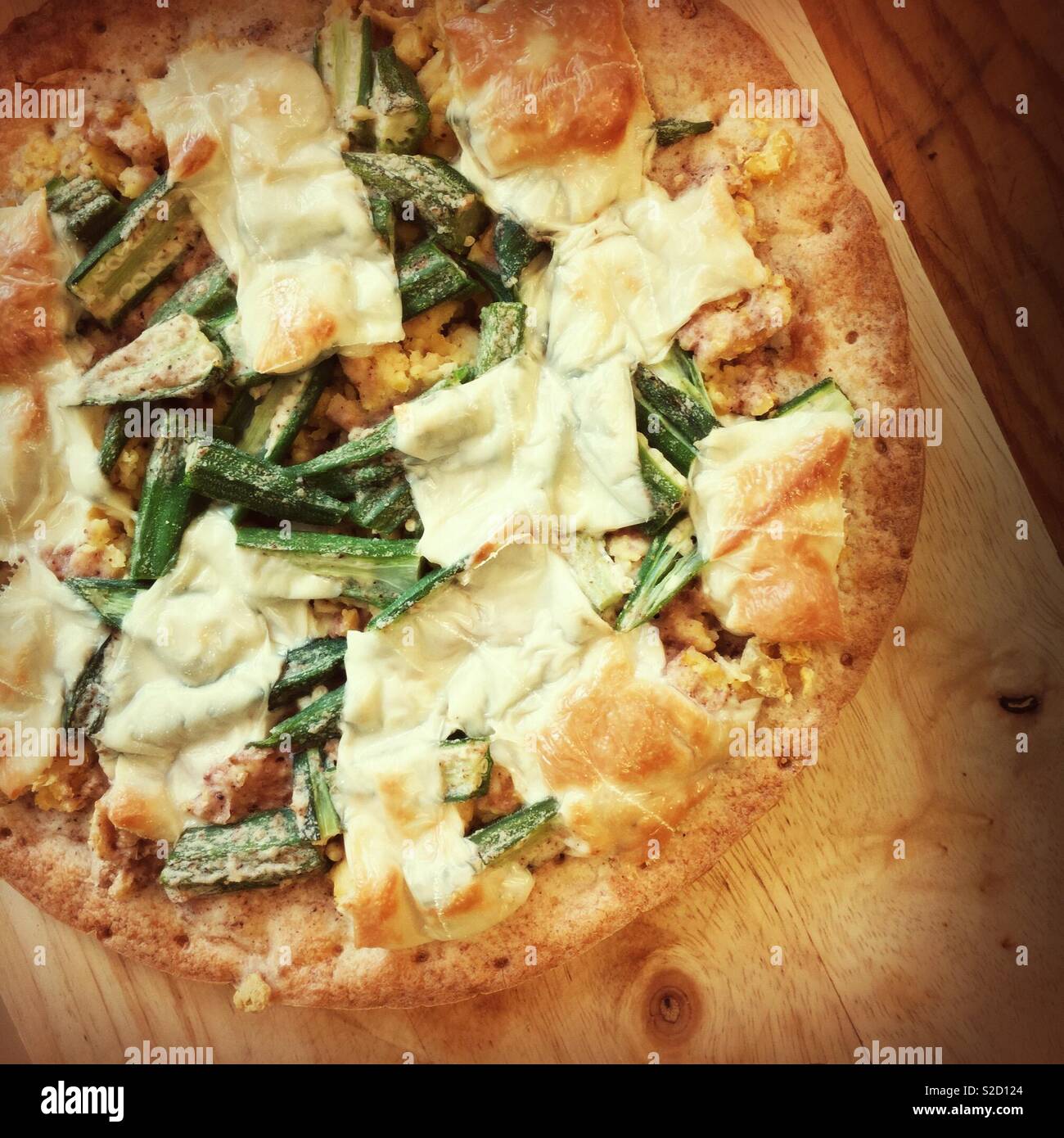 In casa senza glutine senza lattosio vegan pizza bianca su un bambù tagliere su un tavolo di legno. L'okra, ceci, e mozzarella vegana su un senza glutine di crosta. Sano cibo contemporanea. Serie - Immagine stock catturata con smartphone
