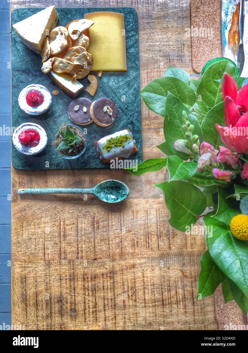 Il dessert e formaggi piatto sul tavolo in legno con bouquet floreali Foto Stock