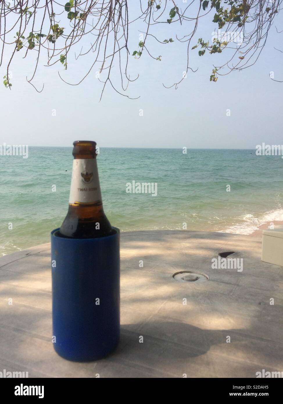 Bottiglia di birra sul tavolo con vista sul mare Foto Stock