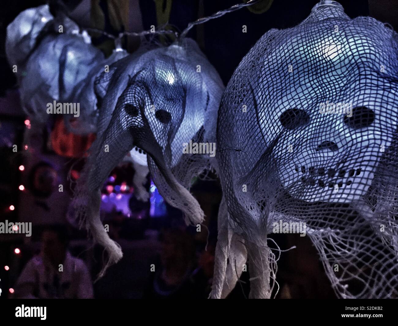 Una fila di inquietanti lanterne teschee drappeggiate in tessuto, che proiettano ombre spaventose, perfette per le decorazioni di Halloween o per creare un'atmosfera da casa infestata dai fantasmi Foto Stock