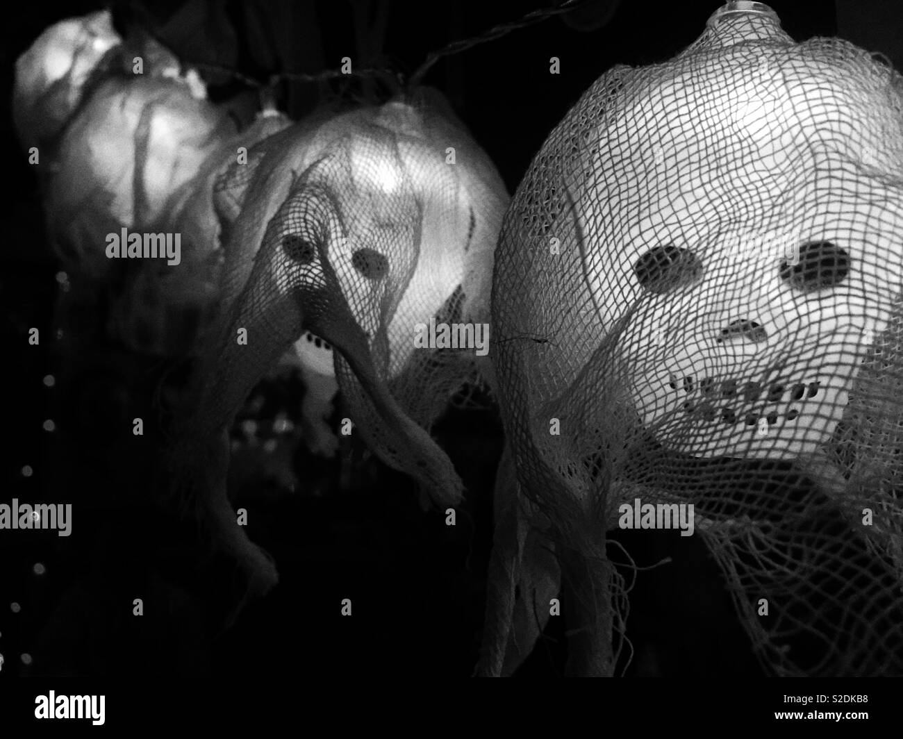 Una fila di inquietanti lanterne teschee drappeggiate in tessuto, che proiettano ombre spaventose, perfette per le decorazioni di Halloween o per creare un'atmosfera da casa infestata dai fantasmi Foto Stock Una fila di inquietanti lanterne teschee drappeggiate in tessuto, che proiettano ombre spaventose, perfette per le decorazioni di Halloween o per creare un'atmosfera da casa infestata dai fantasmi Foto Stock