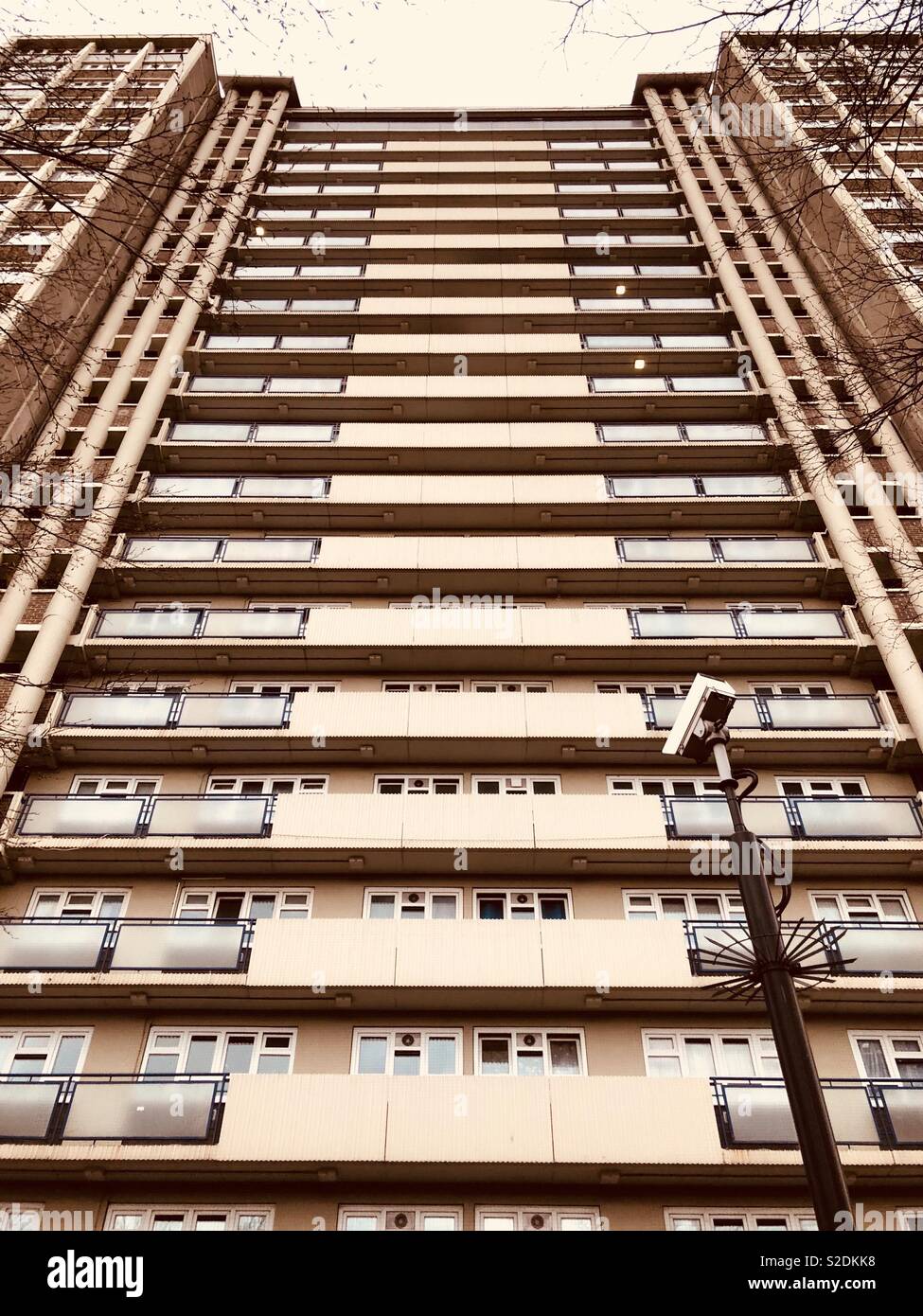 Paesaggio urbano di Londra e moderno isolato a torre con le telecamere di sicurezza, telaio in inverno i rami degli alberi presi da angolo basso Foto Stock