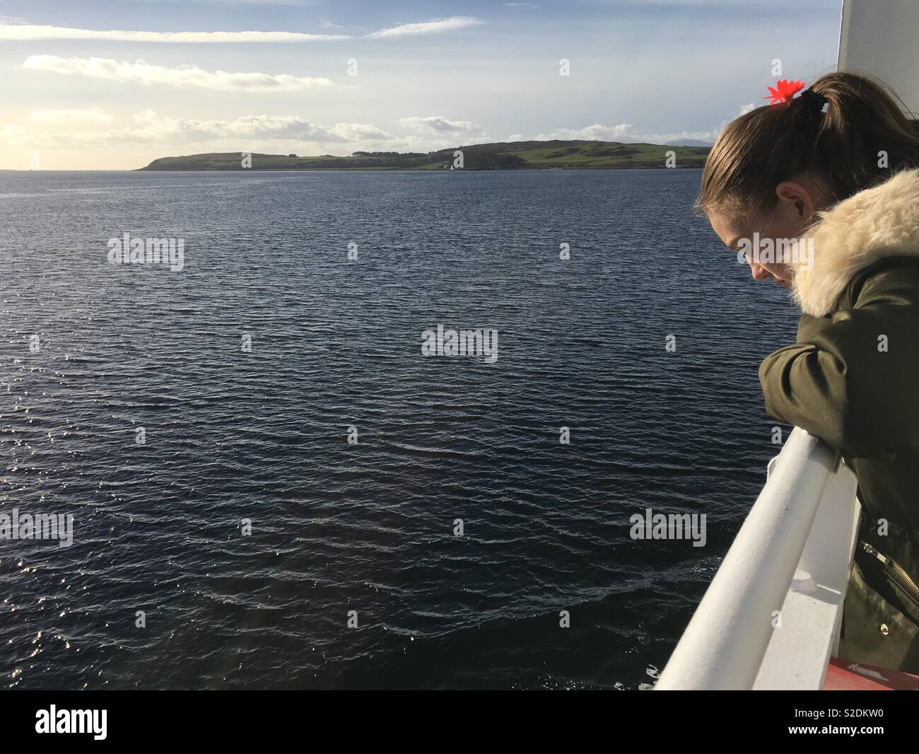 Un 13-anno-vecchia ragazza sguardi verso il basso nell'acqua, dal ponte di una nave traghetto sul Firth of Clyde in Scozia. Foto Stock