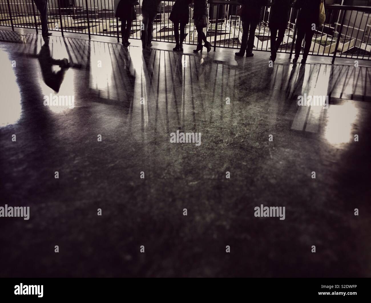 Ombre di gambe e piedi in uno spazio interno con una lucida riflettente piano Foto Stock