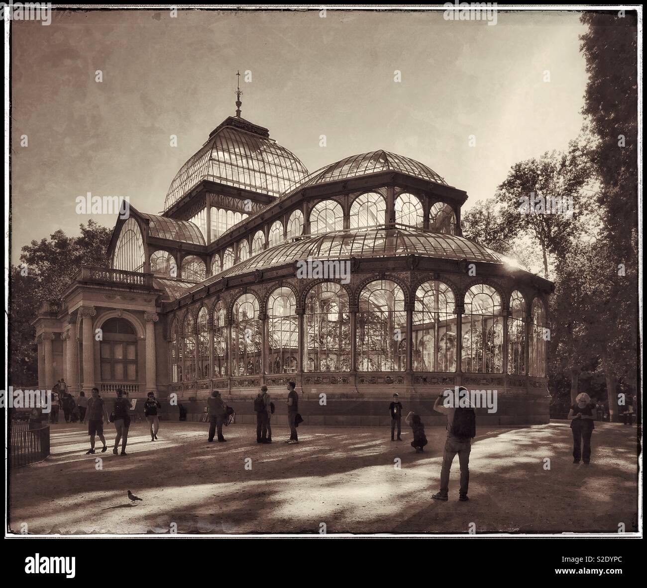 Un effetto retrò immagine di visitatori a piedi attorno al Palacio de Cristal (Crystal Palace) a Madrid il Buen Retiro Park - un deve vedere la struttura architettonica. Foto © COLIN HOSKINS. Foto Stock