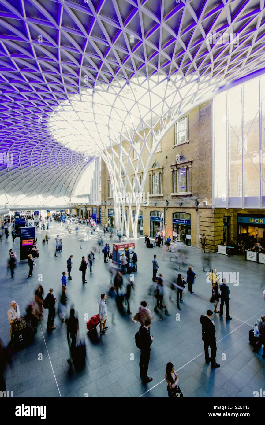 Il concourse ed elaborare il tetto della stazione dei treni di Kings Cross con pendolari, passeggeri e viaggiatori in attesa per i treni Foto Stock