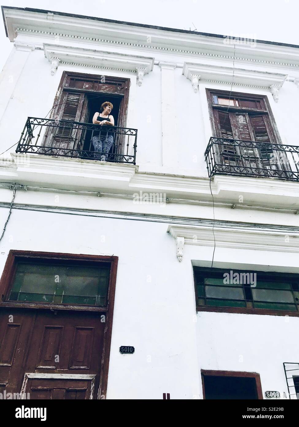 Signora su un balcone di una casa in stile coloniale a Cuba Foto Stock