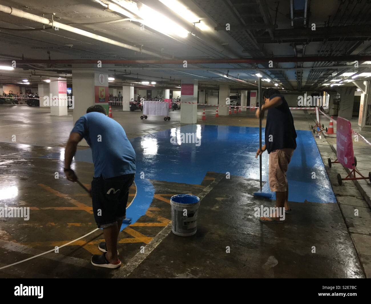 I lavoratori sono la verniciatura vernice epossidica di colore blu sul parcheggio auto piano. Foto Stock