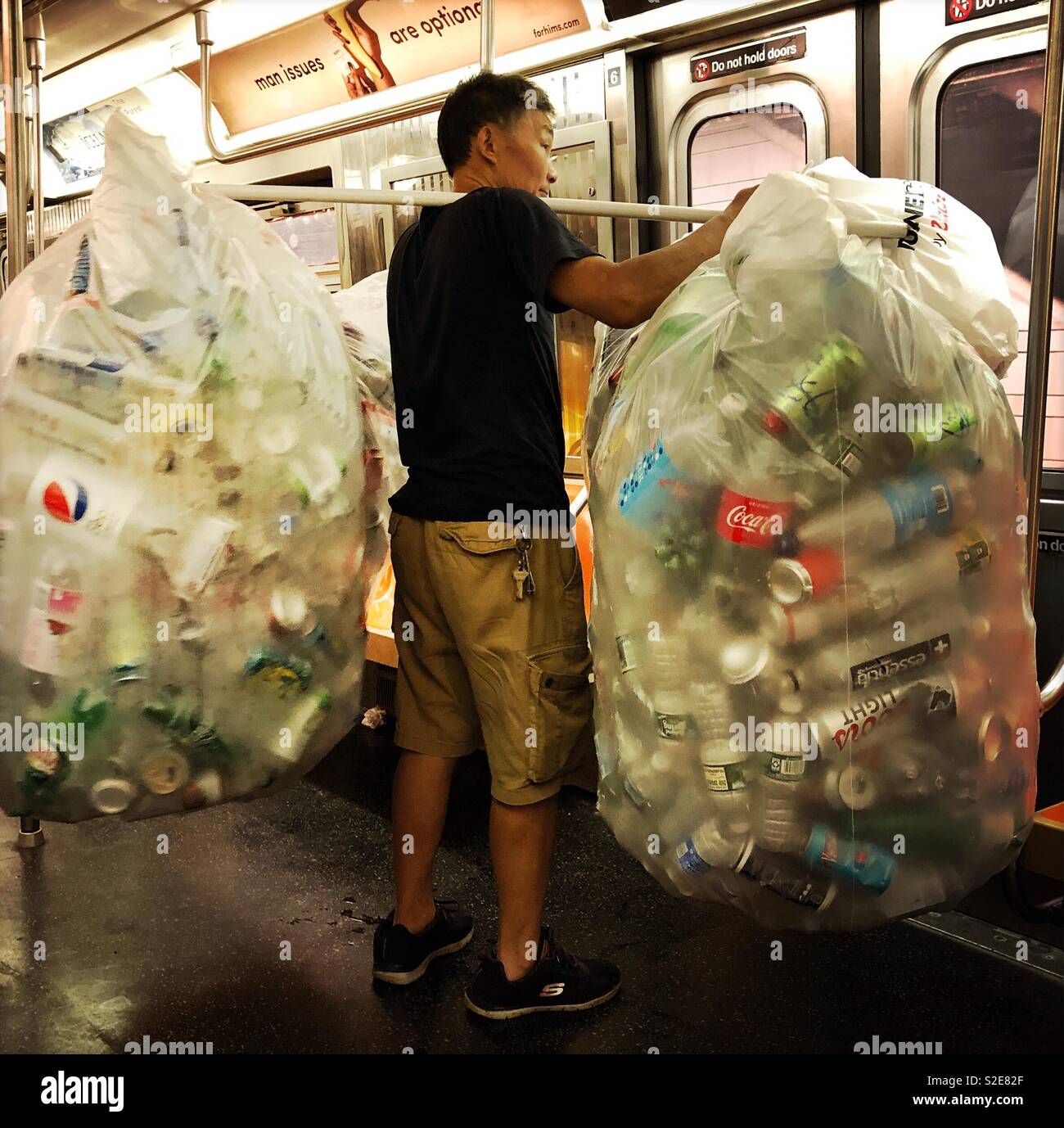 L'uomo con la collezione di bottiglie e lattine in sella alla metropolitana Foto Stock