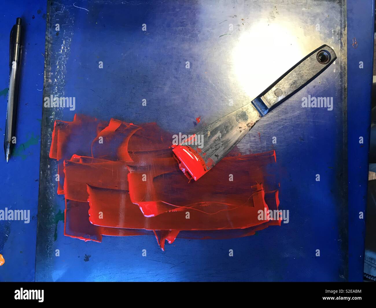 Coltello per stampanti con inchiostro rosso su sfondo blu Foto Stock