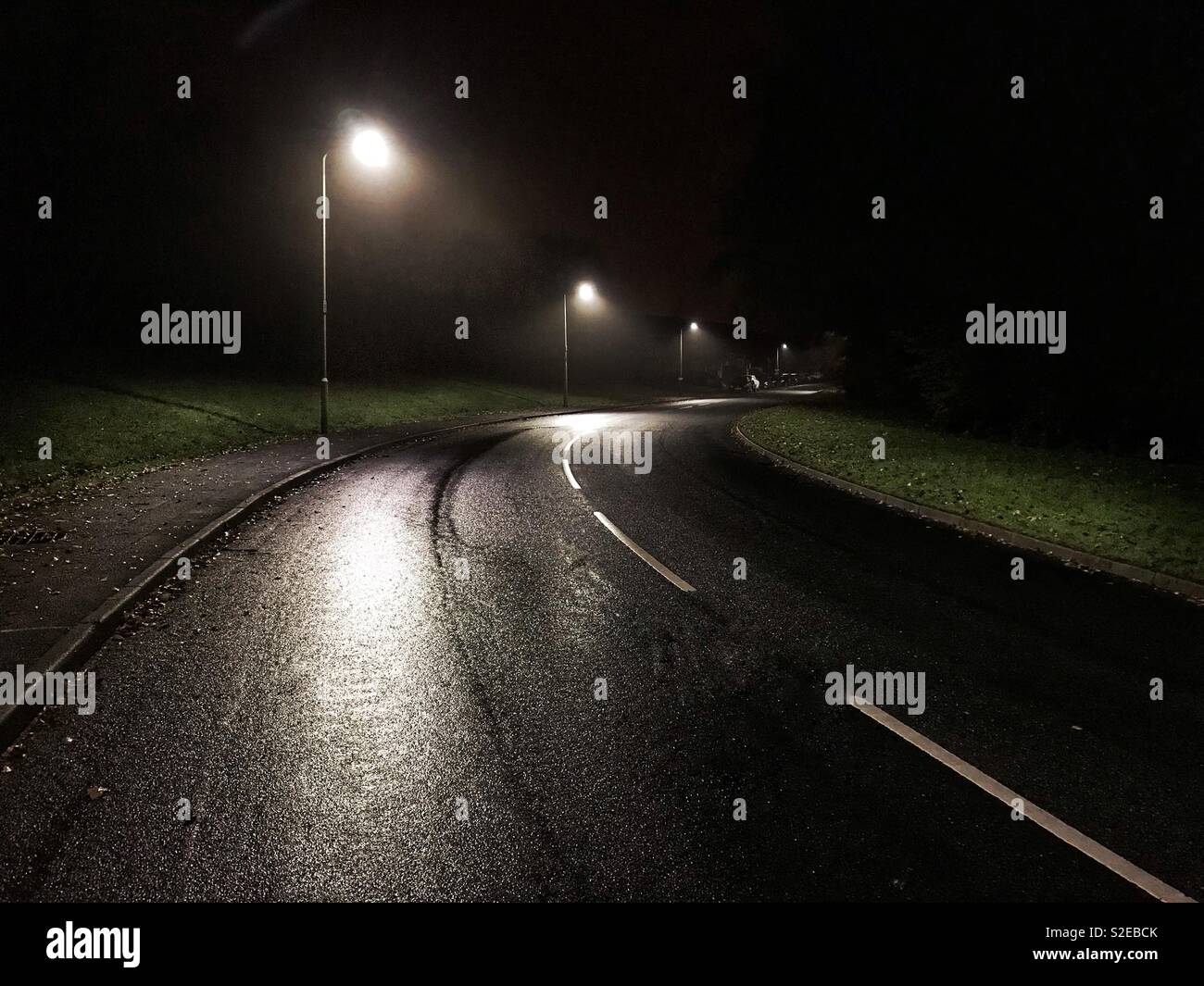 Le luci di strada su una strada solitaria a tarda notte Foto Stock