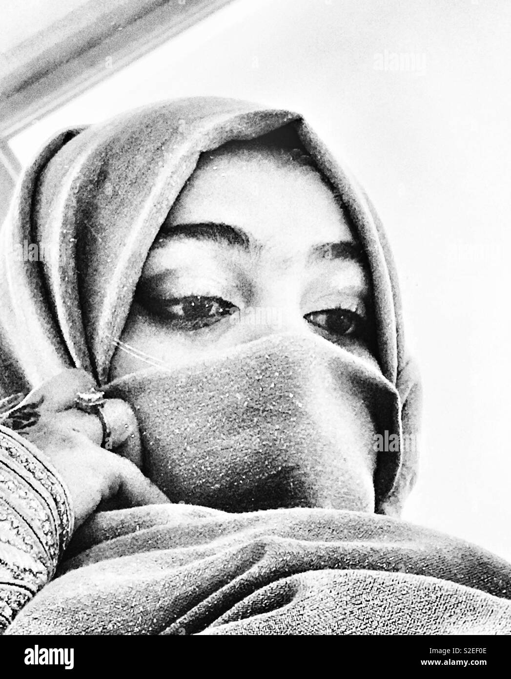 Una velata Arabian girl guardando la sua riflessione dal mirror Foto Stock