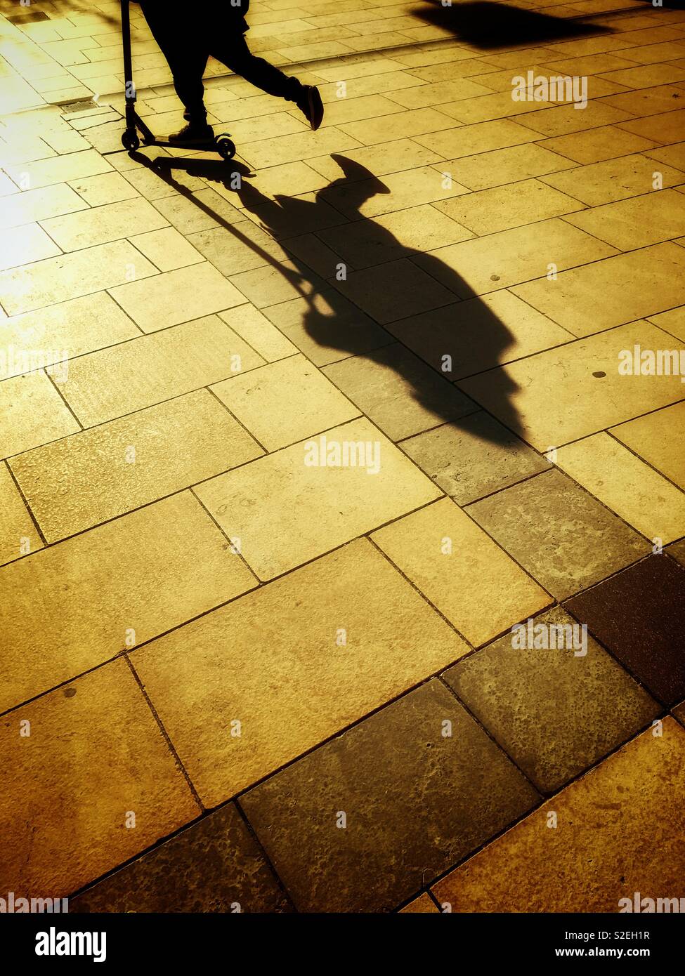 Ombre di un ragazzo su uno scooter sul marciapiede Foto Stock