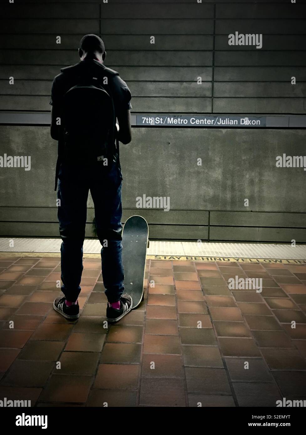 Giovane americano africano uomo attende con lo skateboard per la Metro treno su piattaforma in 7th Street Metro Center in downtown Los Angeles - Immagine stock catturata con smartphone