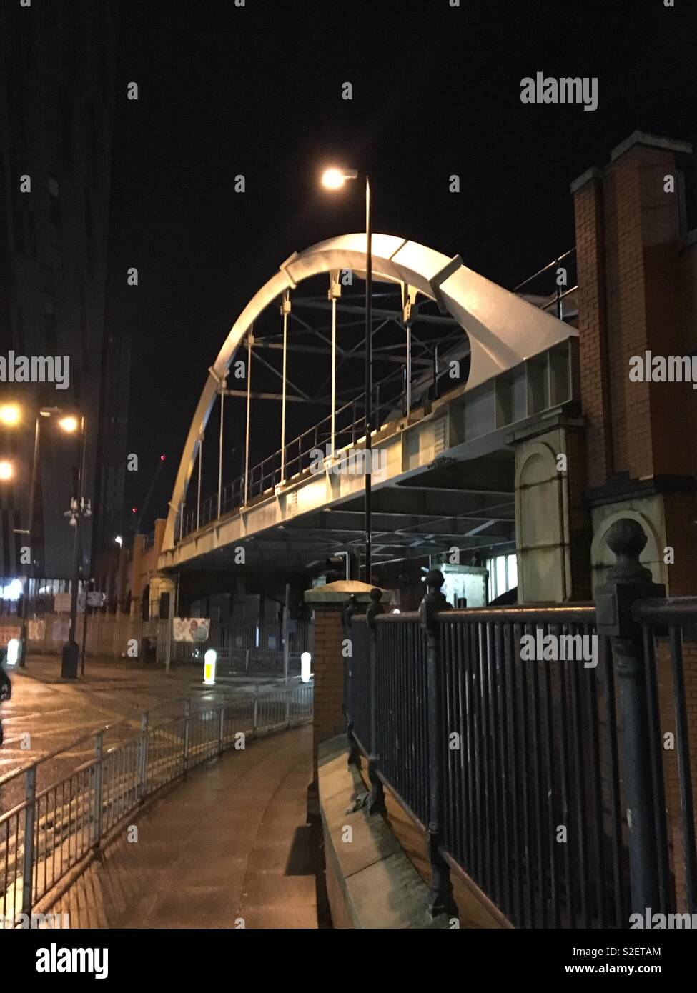 Ponte ferroviario al di sopra di una strada nella zona centrale di Manchester, UK di notte Foto Stock