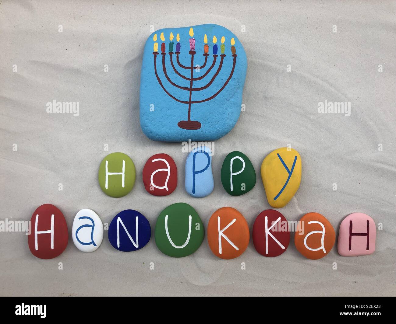 Happy Hanukkah, festival ebraico di luci celebrata con pietre colorate sulla sabbia bianca Foto Stock