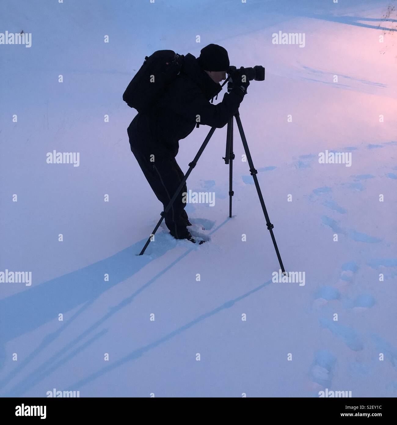 Fotografo maschio con treppiede nella neve profonda. Foto Stock