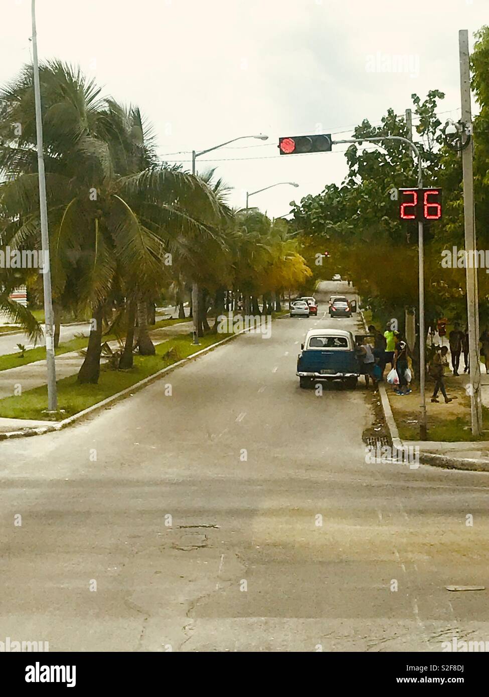 Una strada con auto classiche, i semafori e le palme in Havana Cuba Foto Stock