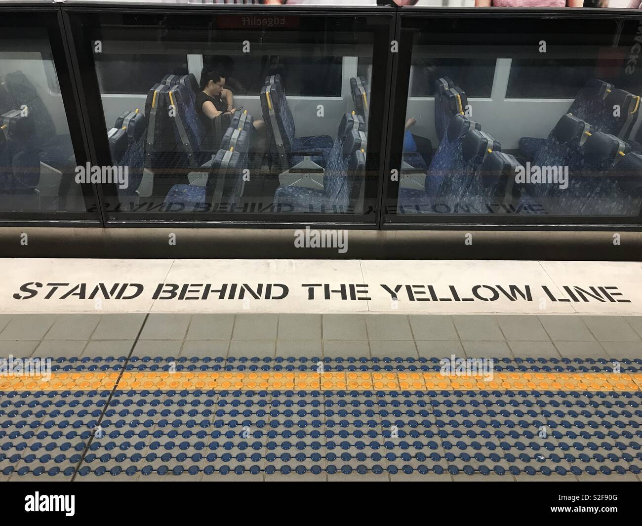 Stare dietro la linea gialla avviso a Sydney la stazione ferroviaria. - Immagine stock catturata con smartphone