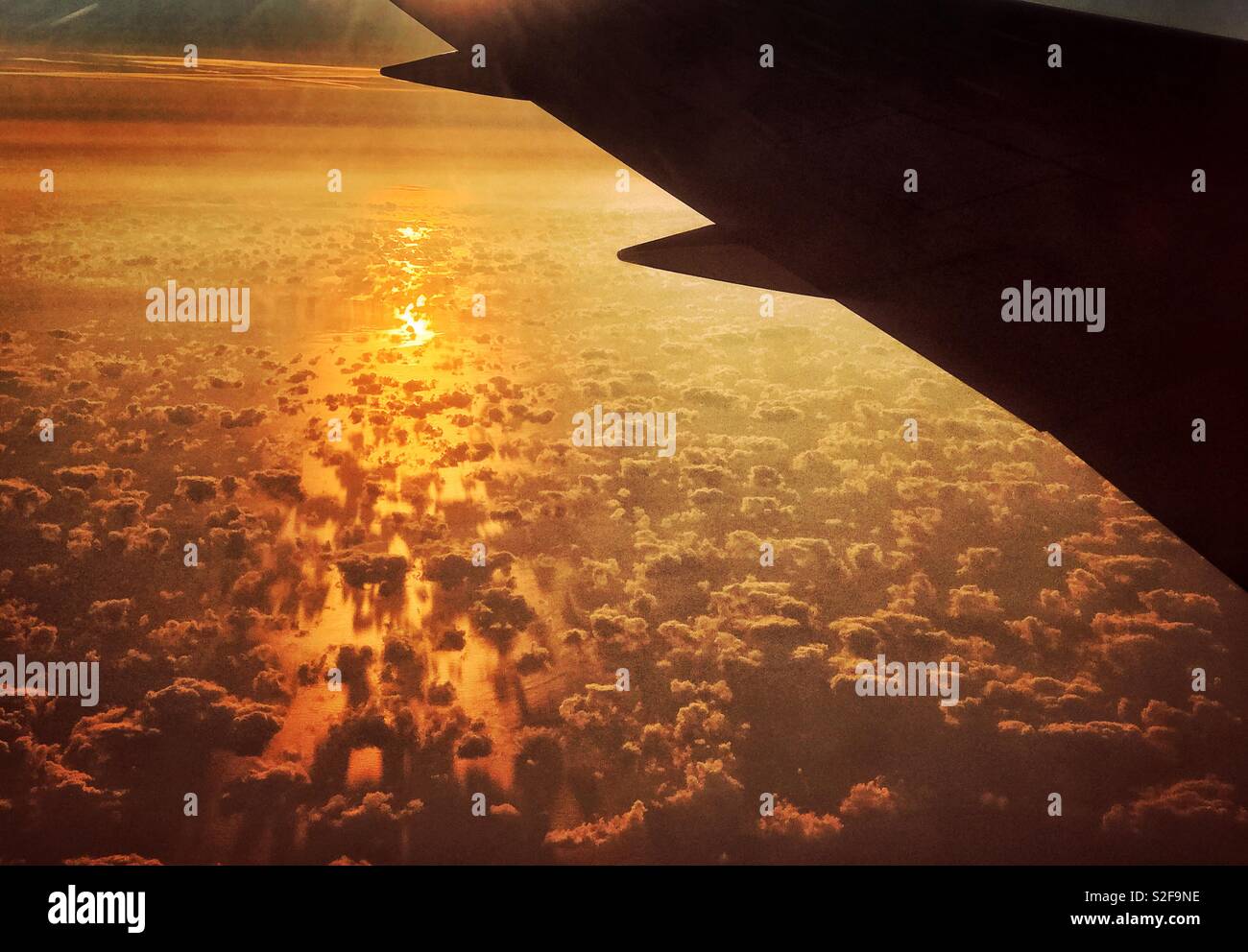 La vista dal finestrino per aerei guardando il tramonto sul Golfo di Biscaglia. Spia gialla viene riflesso dall'Oceano Atlantico &aiuta a delineare le interessanti formazioni di nubi. Foto © COLIN HOSKINS. - Immagine stock catturata con smartphone