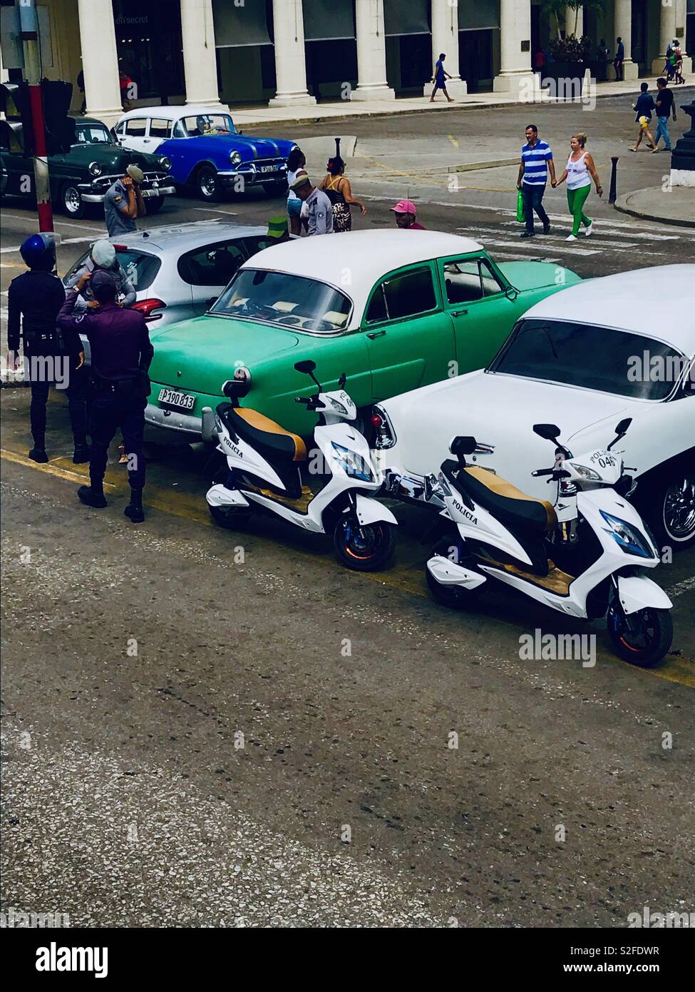 La polizia e la polizia moto parcheggiata fino a fianco di auto classiche nel centro della città di Havana Cuba Foto Stock