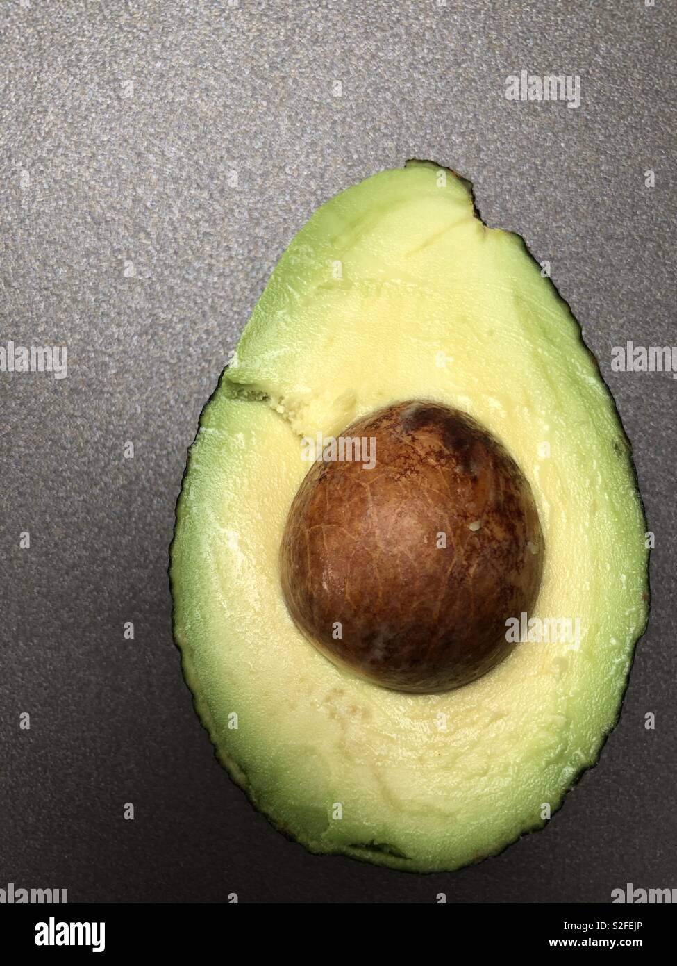 Perfettamente mature avocado tagliato a metà per rivelare la carne e la pietra Foto Stock