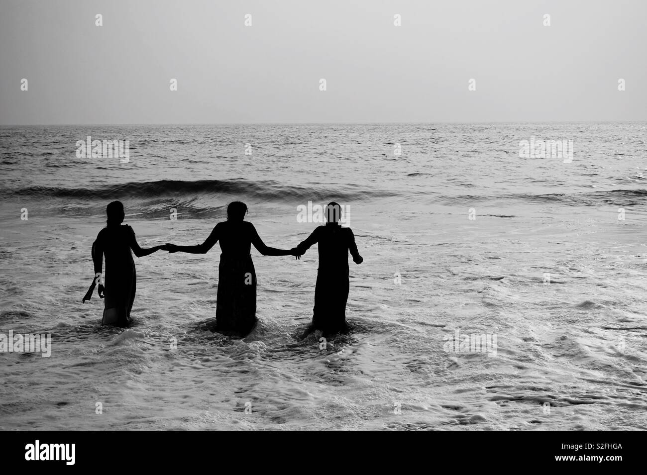 Tre donne prendere un bagno in mare Foto Stock