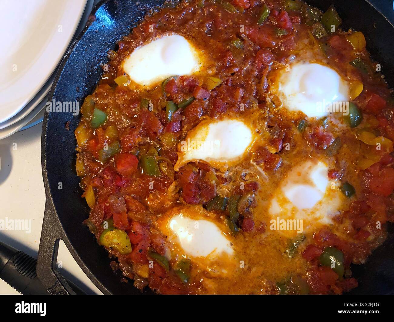 Le pietanze mediterranee, shakshouka o shakshuka - uova in camicia in una salsa di pomodori, i peperoni e le cipolle con spezie e aglio - Immagine stock catturata con smartphone