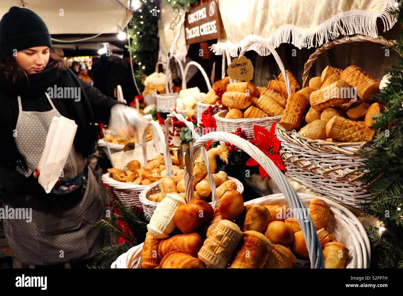 Un chiosco di cibo al mercato di Natale di Cracovia vende pane e cibi caldi, creando un'atmosfera di vacanza calda e accogliente con prelibatezze tradizionali polacche - Immagine stock catturata con smartphone