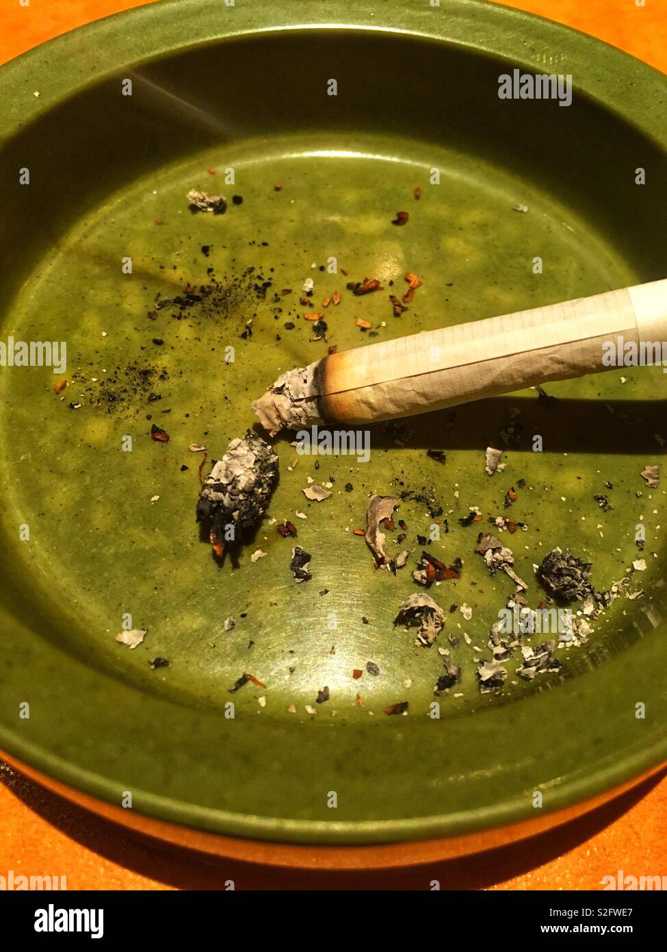 Sigaretta accesa nel posacenere Evergreen-Colored Foto Stock