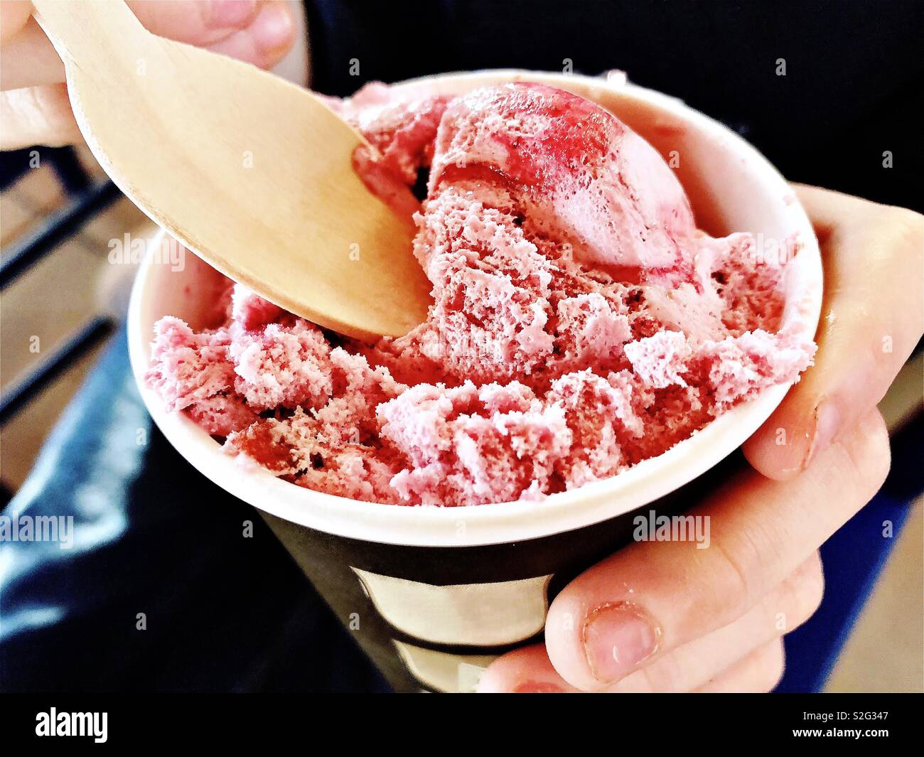 Gelato alla fragola in bicchiere di carta con il cucchiaio di legno Foto Stock